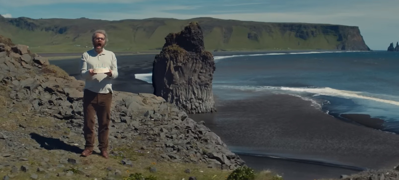Traveler standing near Iceland black sand beach cliffs, capturing the dramatic scenery that makes Iceland road trips unforgettable.