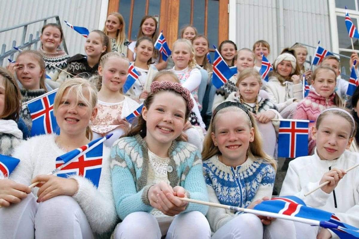 A group of Icelandic children waving flags and dressed in traditional Icelandic sweaters, celebrating national heritage