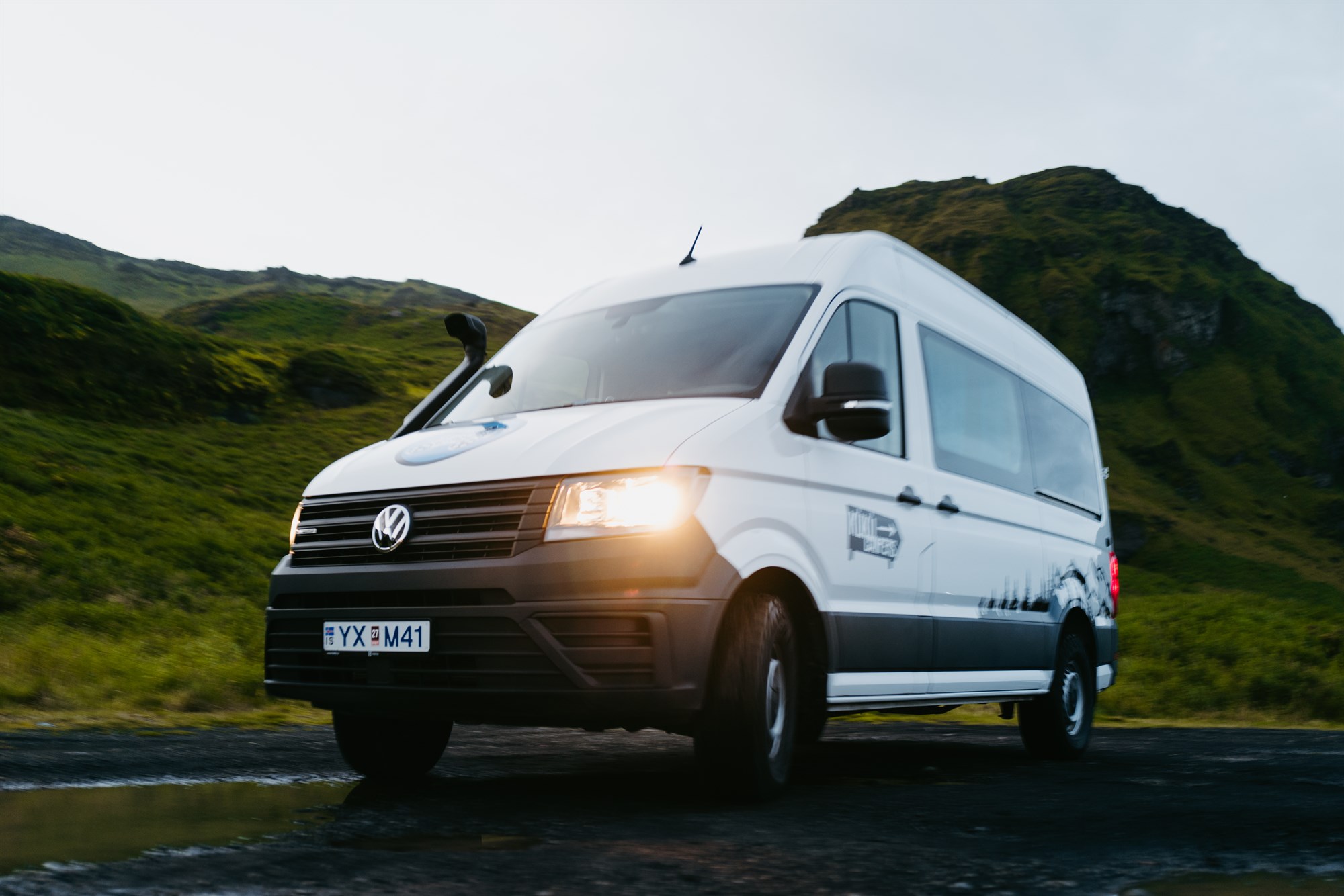 A white KuKu campervan driving through the Icelandic highlands, ready for adventure.