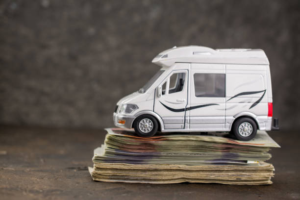 Toy van on a stack of bills illustrating security deposit requirements for Iceland camper rental.