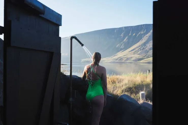 Outdoor shower near Icelandic fjords, combining road trip freedom with one of the strangest shower views on Earth.