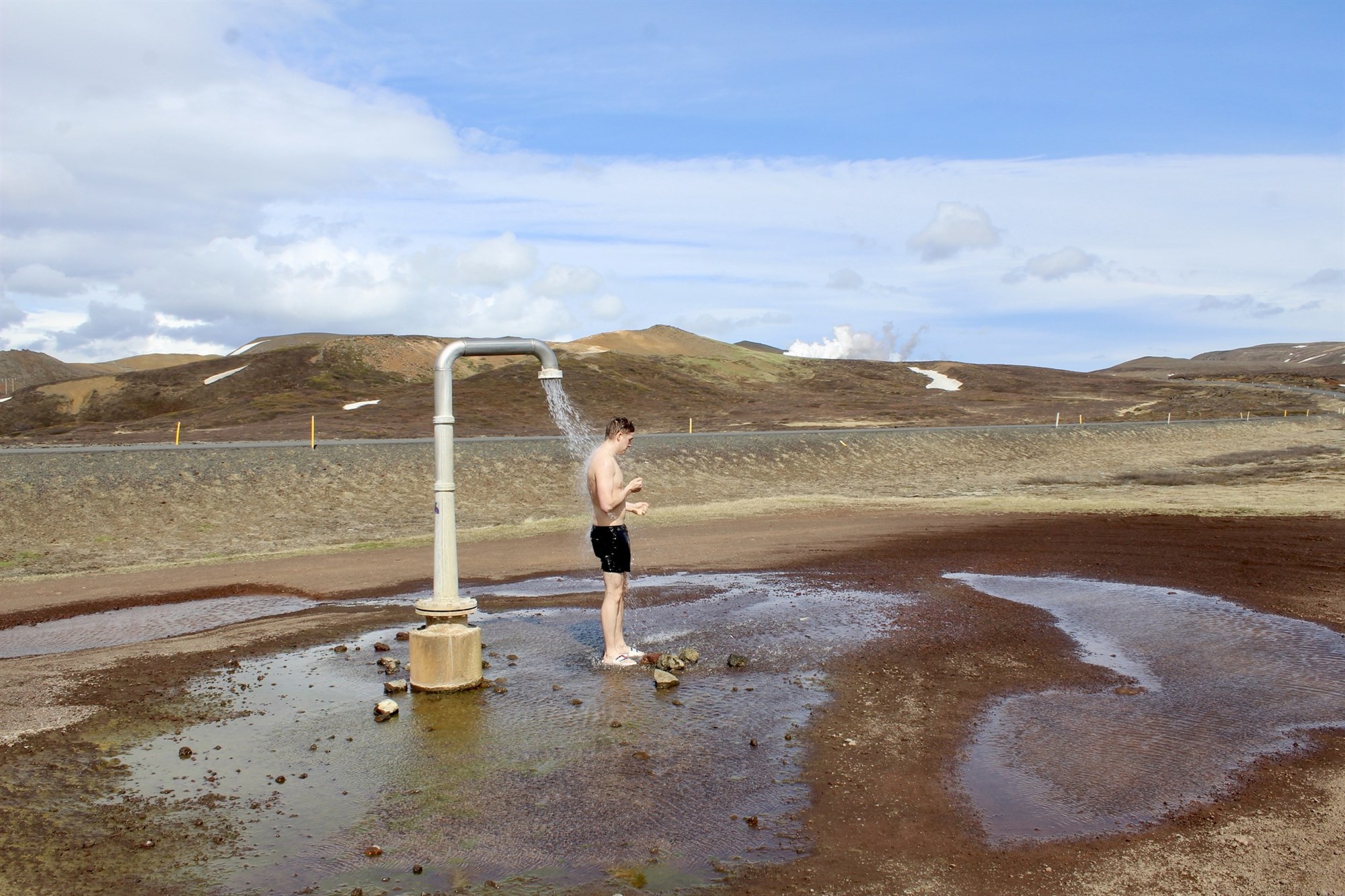 Open air geothermal shower in Iceland surrounded by volcanic landscapes and rugged Highlands scenery.