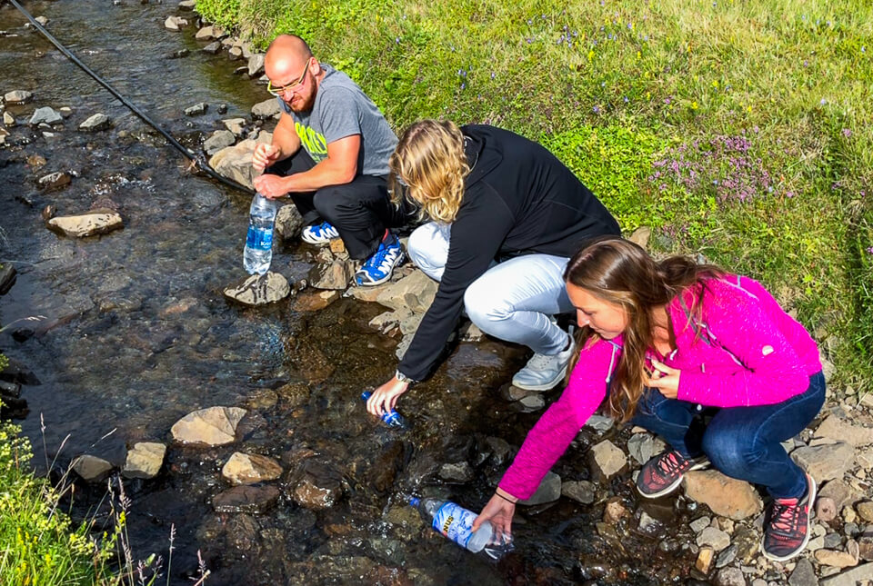Travelers collecting water from a stream in Iceland, illustrating real conditions when drinking natural water sources.