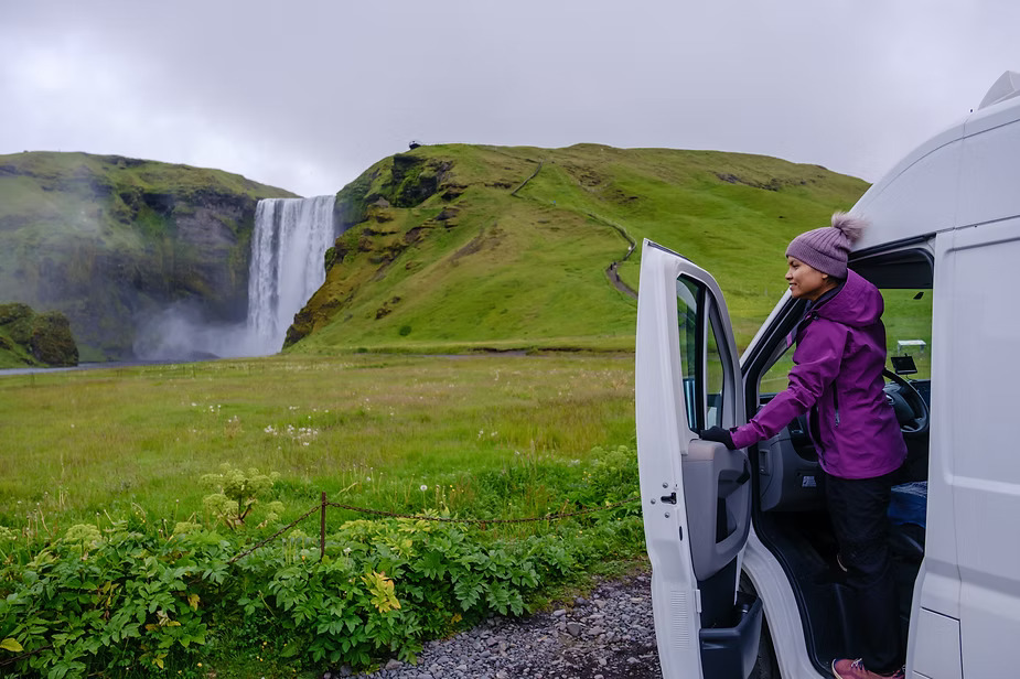 Campervan parked by Iceland waterfall, easy water access on road trip